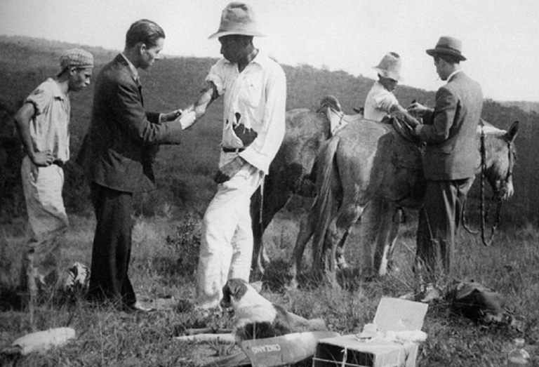 Profissionais de saúde vacinam trabalhadores do campo contra a febre amarela no início dos anos 30. A foto foi capa de um livro lançado em 2002 pela Fiocruz sobre a saga do combate à doença no Brasil desde 1937