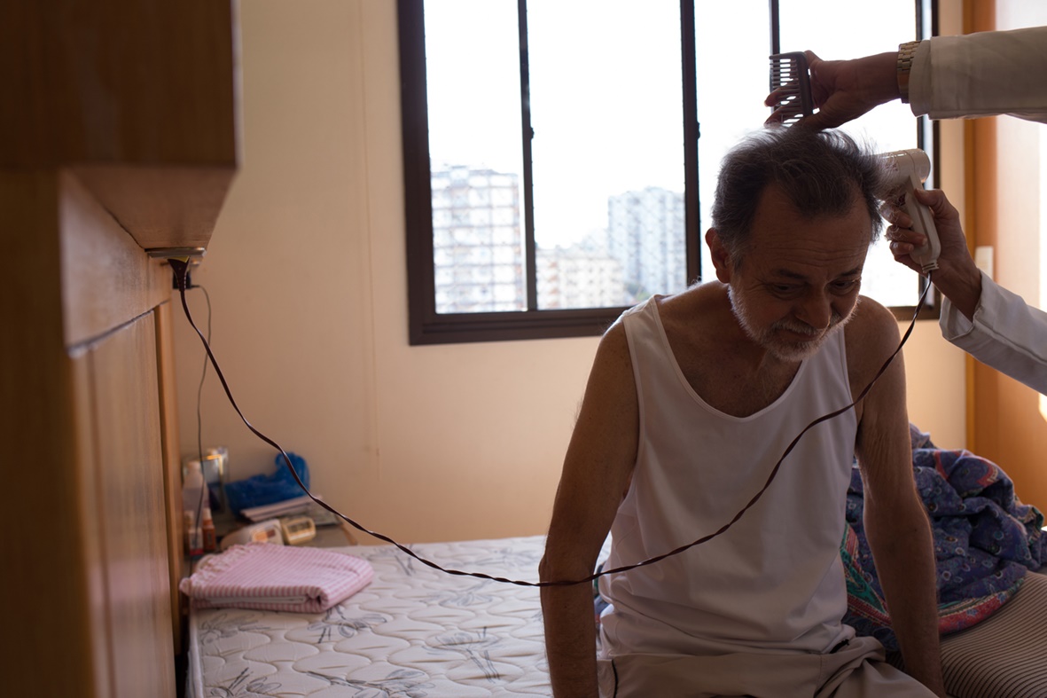 Valda Nogueira Paulo secando seu cabelo com a ajuda da enfermeira J. antes de ir ao Hospital são Francisco de Assis para uma consulta médica