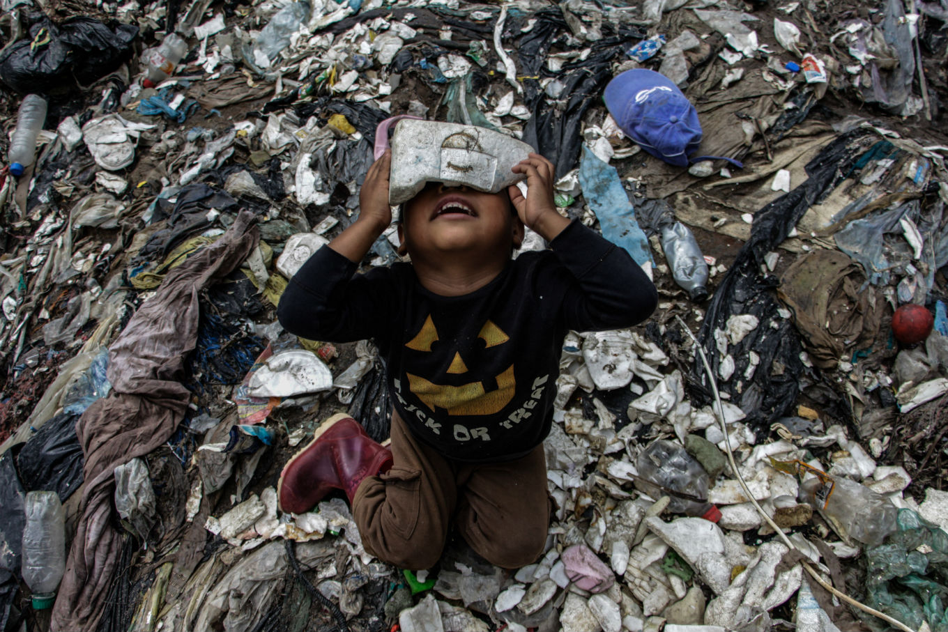 Foto de Josue Decavele/Anadolu Agency/ AFP Menino brincando no lixo. Foto de Josue Decavele/ Anadolu Agency/ AFP