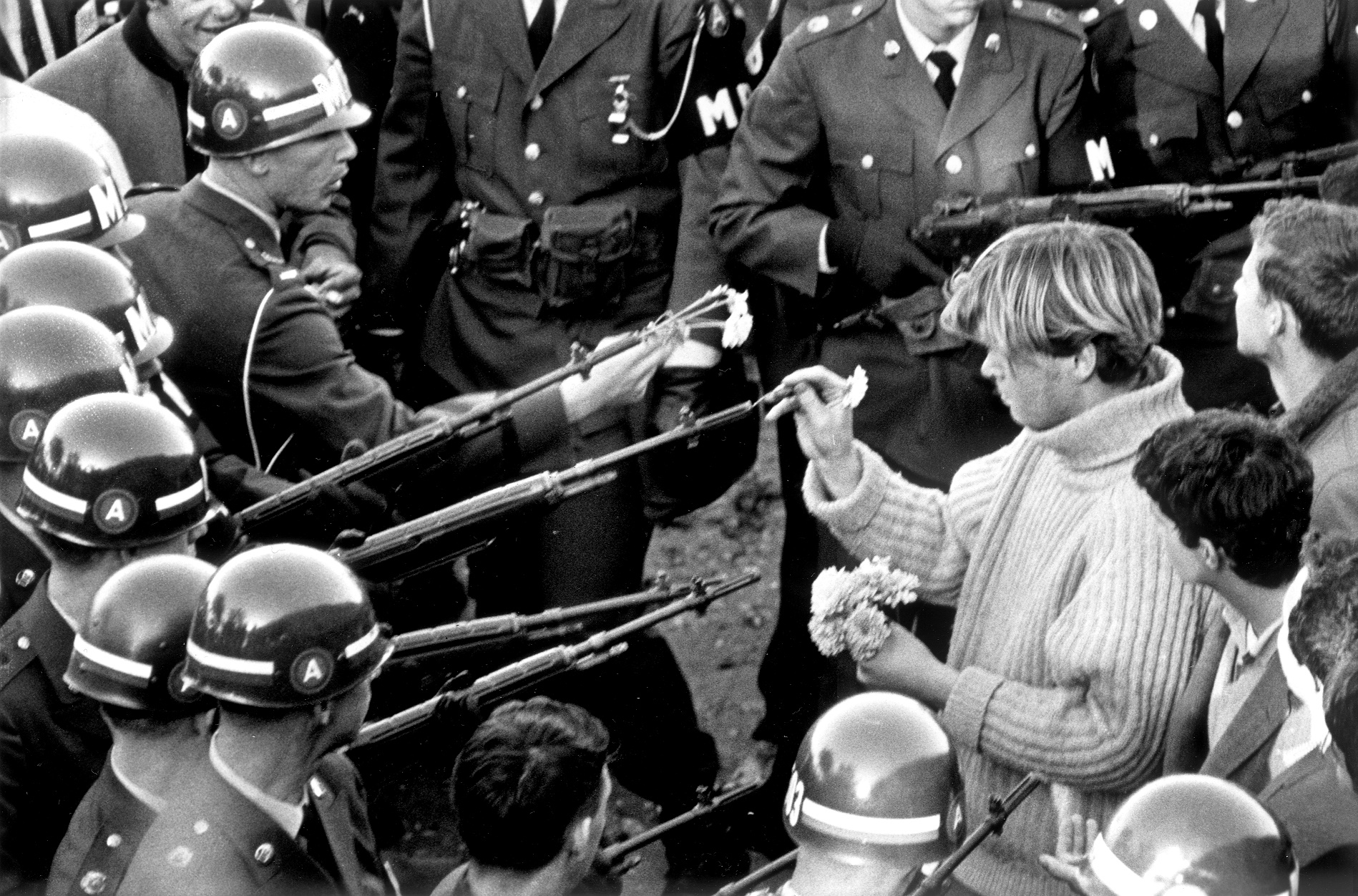 Em 1967, em frente ao Pentagono, nos EUA, um ativista põe flores no cano das armas. Foto de Bernie Boston/The Washington Post/via Getty Images
