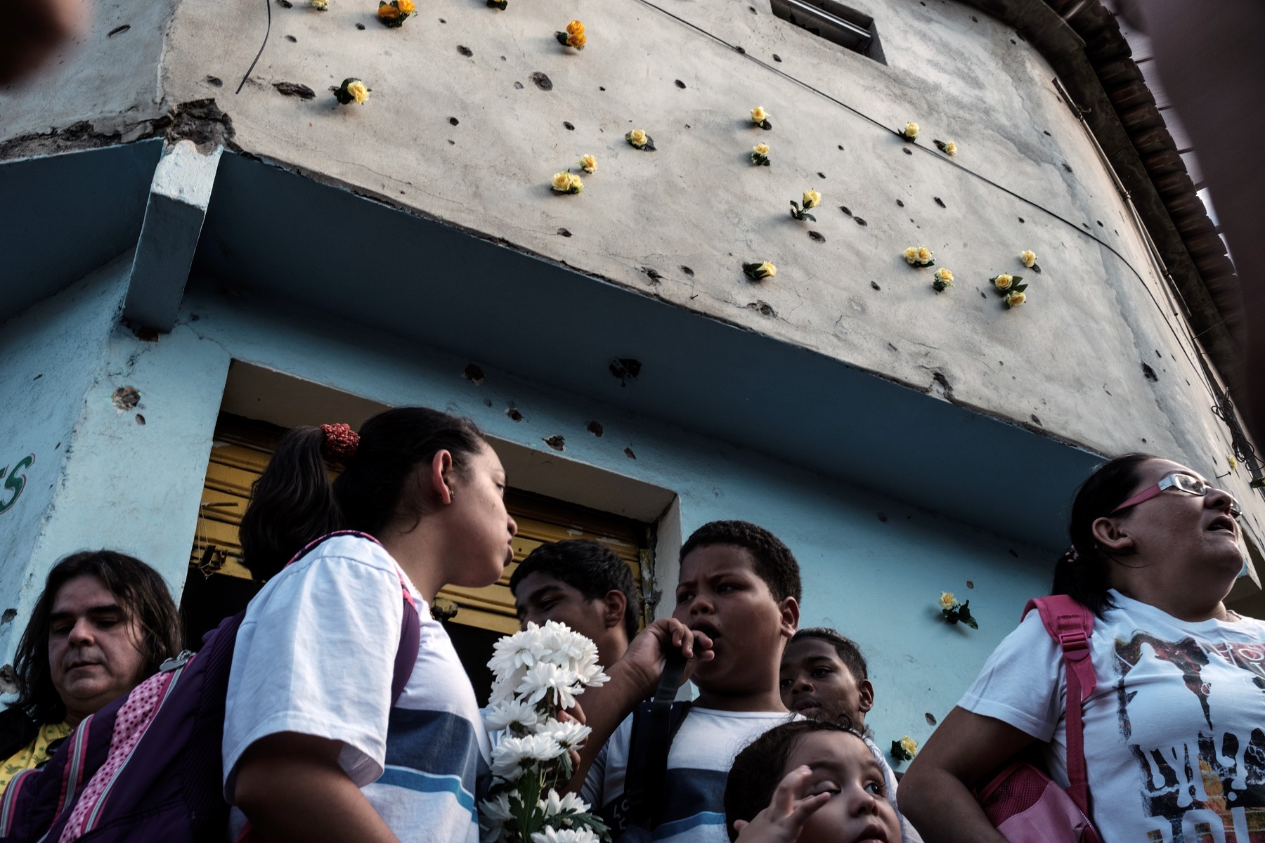 Foto Yasuyoshi Chiba/AFP Crianças das escolas públicas da região põem flores nos buracos de bala das paredes. Foto Yasuyoshi Chiba/AFP