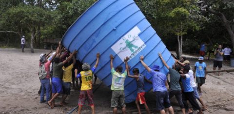 Ribeirinhos da comunidade de Anumã, no Tapajós, carregam caixa d'agua comunitária (Foto Chico Ferreira/Divulgação)