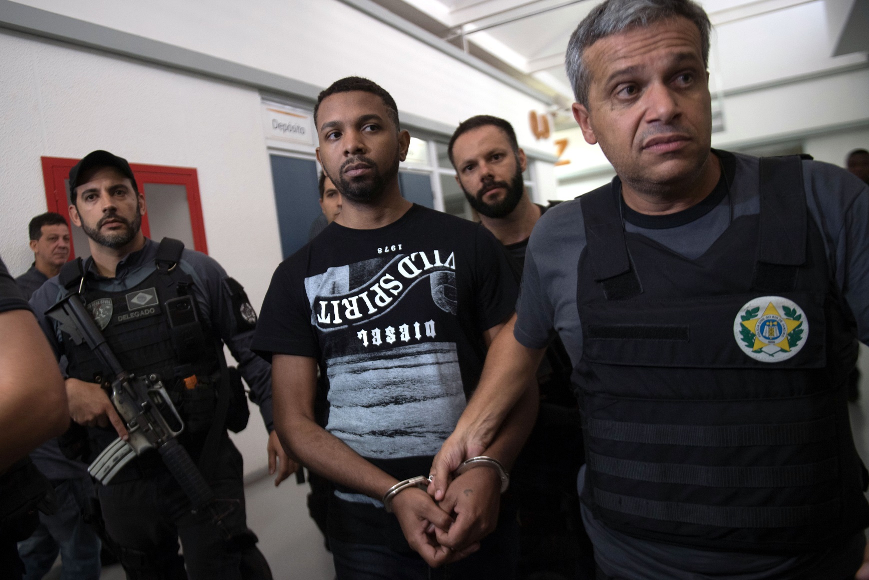 Rogério Avelino da Silva (C), o Rogério 157,chega algemado à delegacia. Foto Mauro Pimentel/AFP