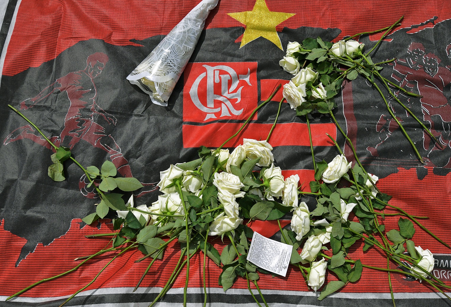 Flores sobre a bandeira do Flamengo. Luto pela tragédia que matou dez pessoas. Foto Carl de Souza/AFP