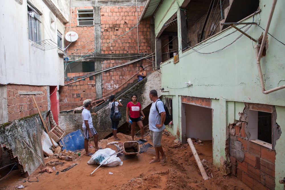 Sobre o monte de terra que soterrou a casa de Clarencio (de costas), voluntários cadastram moradores atingidos pela chuva (Foto Kita Pedroza)