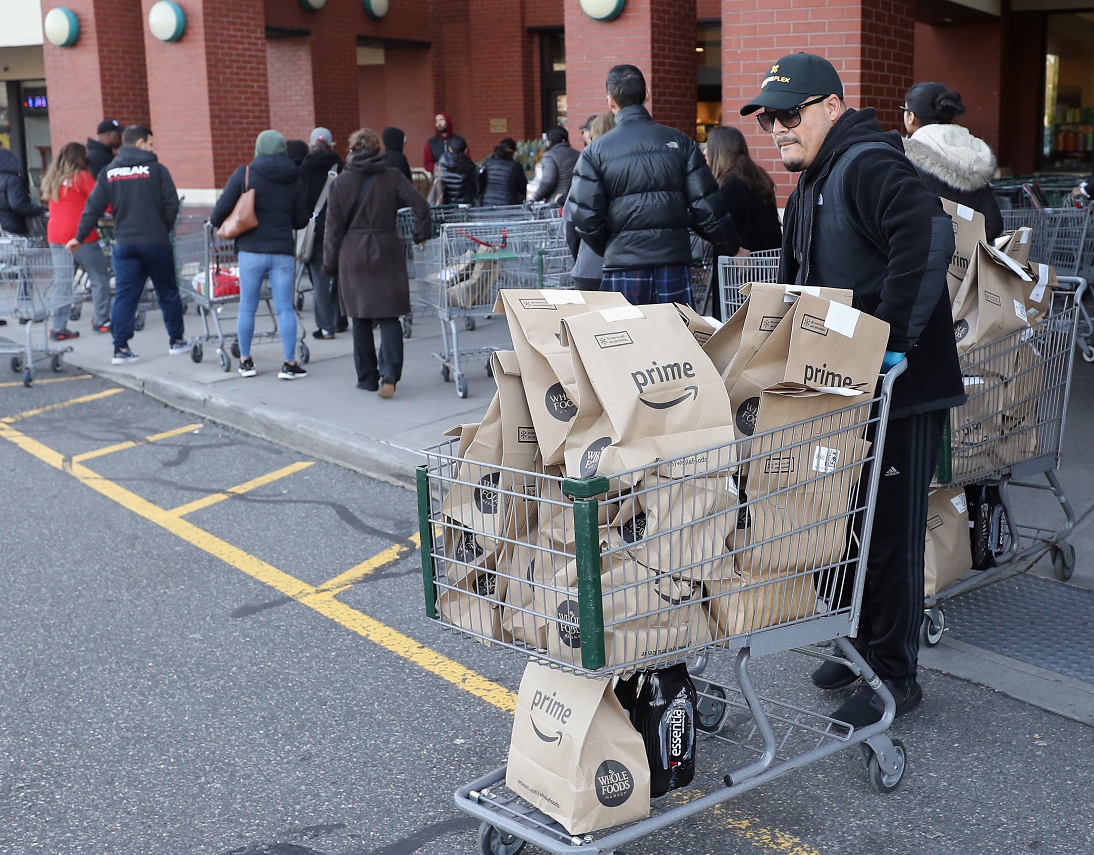 Entregador da Whole Foods, supermercado da gigante de tecnologia Amazon, no depósito da empresa em Nova York: Amazon anunciou contratação de 100 mil pessoas pois pandemia fez exxplodir encomendas, de papel higiênico e alimentos a televisores (Foto: Bruce Bennett/Getty Images/AFP)
