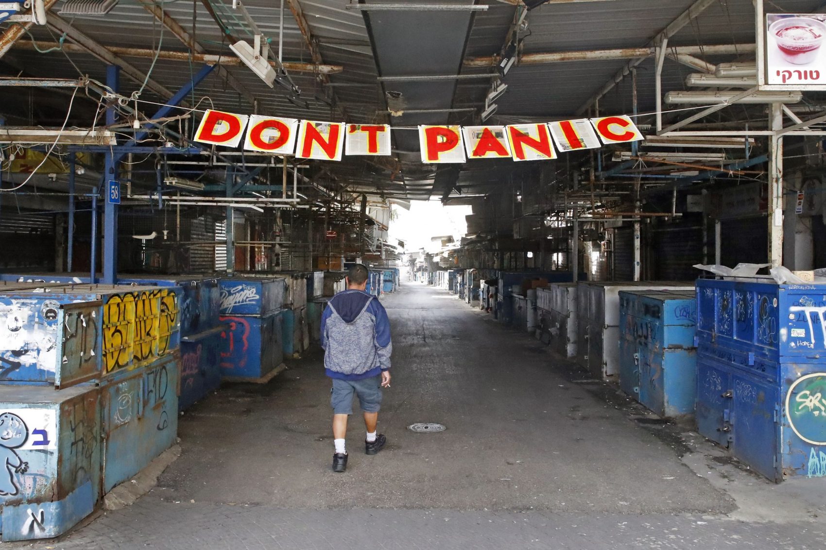 Cartaz contra o pânico em mercado em Tel-Aviv (Israel): psicólogo Steven Taylor lembra que "os humanos sobreviveram a muitas pandemias no passado" (Foto: Jack Guez/AFP)