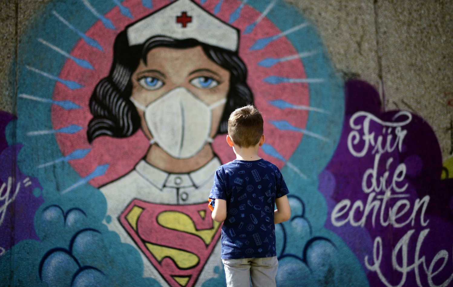 Foto Ina Fassbender/AFP O grafite pintado pelo artista Kai 'Uzey', na Alemanha, chama a atenção do jovem passante. Foto Ina Fassbender/AFP
