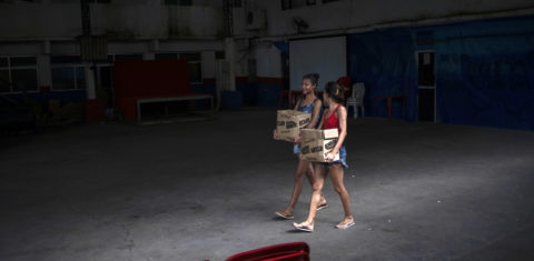 Jovens mulheres carregam caixas com donativos para enfrentar a crise causada pela pandemia na Cidade de Deus: jovens em geral e mulheres em particular terão seu futuro ameaçado pelos impactos da covid-19, alerta consultora da ActionAid (Foto: Mauro Pimentel/AFP)