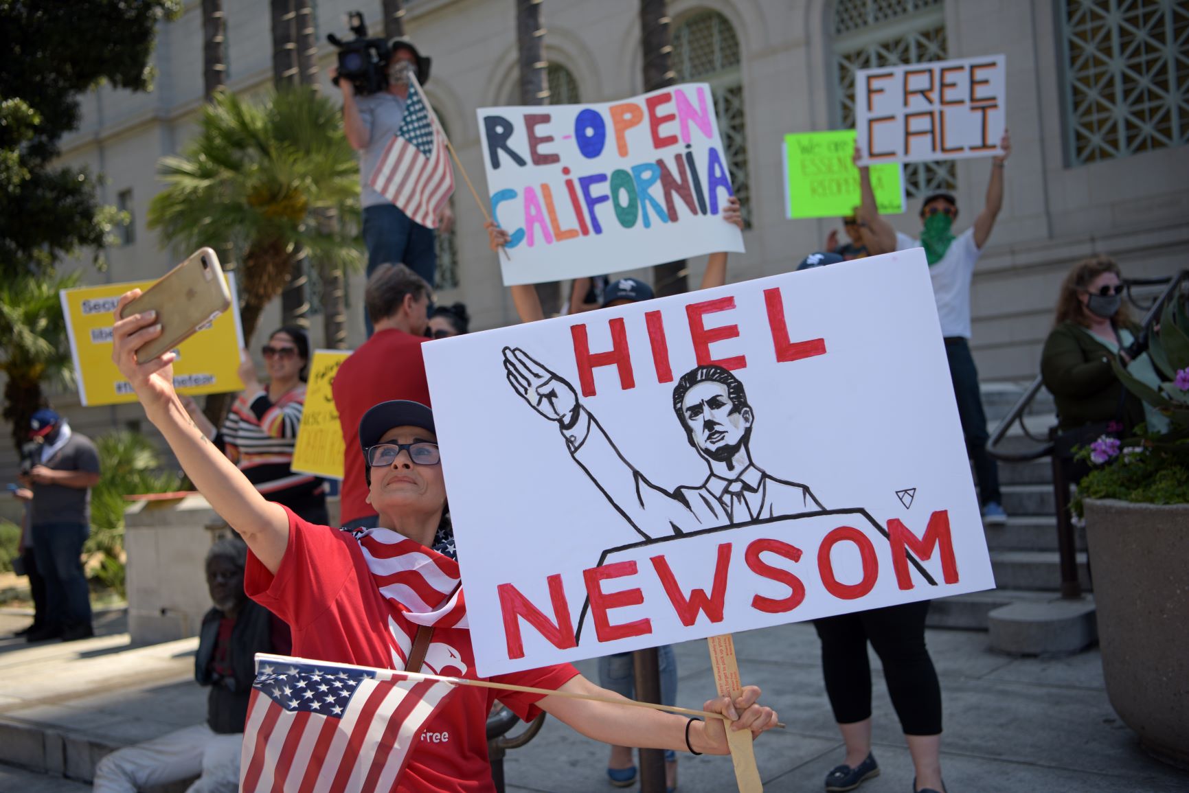 Cartaz compara o governador da Califórnia, Gavin Newsome, a nazista em protesto contra lockdown em Los Angeles: governadores democratas são acusados de "tirania" (Foto: Agustin Paullier/AFP)