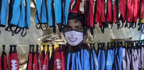 Na cidade de Hyderabad, na Índia, o jovem camelô organiza a sua barraca de máscaras contra a covid-19. foto Noah Seelam/AFP