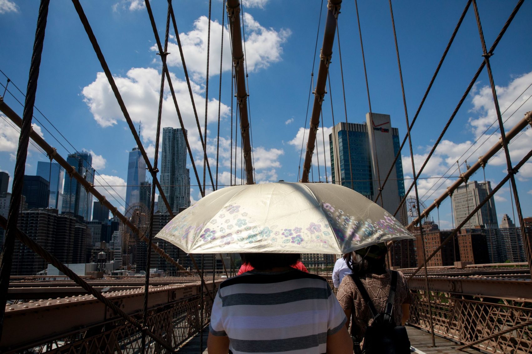 Moradora se protege do sol na ponte do Brooklyn, em Nova YorK: cidade tem abrigos para proteger os mais vulneráveis do calor intenso (Foto: Drew Angerer/AFP)