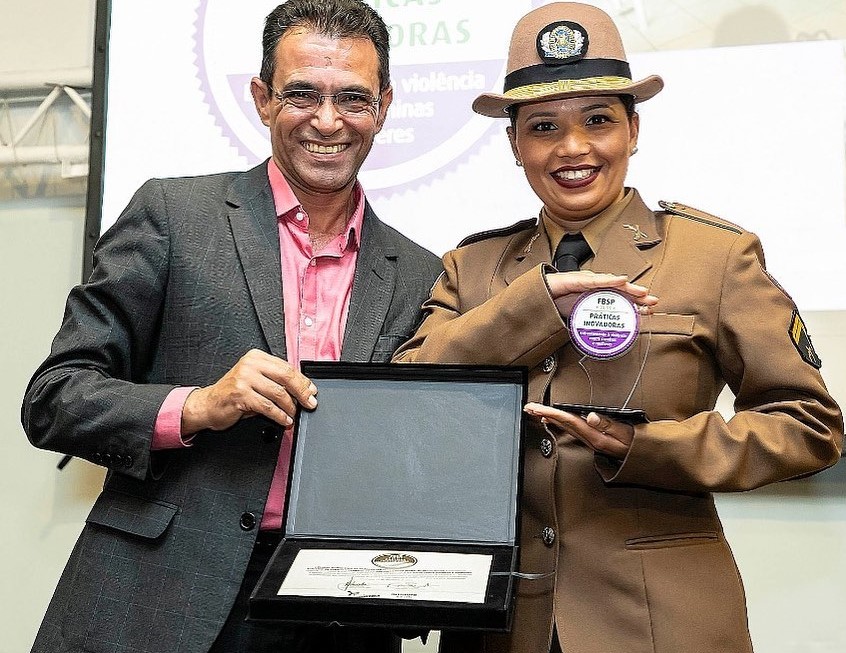 Juliana Lemes da Cruz, responsável pelo projeto Mulher Livre da Violência da PMMG, recebe prêmio das mãos do presidente do FBSP, sargento Elisandro Lotin: alerta para situação no interior de Minas (Foto: Divulgação/FBSP)