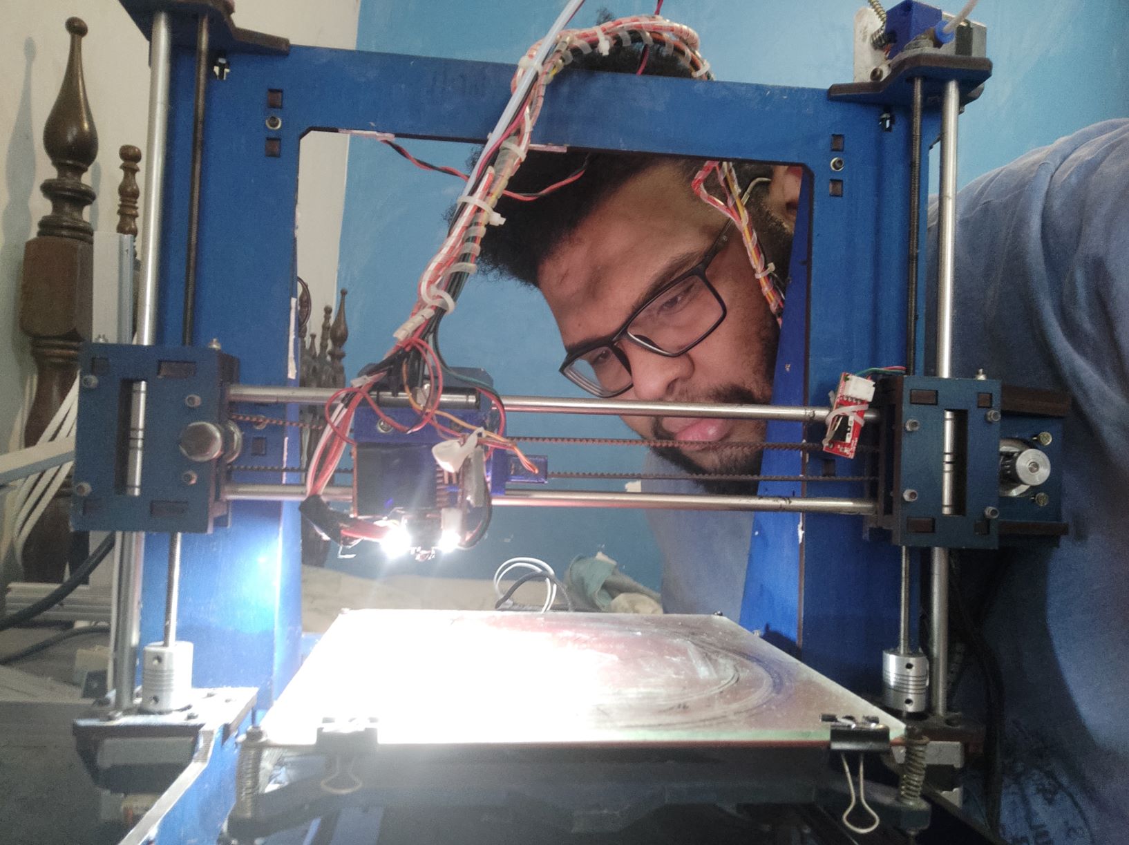 Lucas confere sua impressora 3D feita de sucata eletrônica: máscaras face-shield para unidades da saúde da área Alemão (Foto: Divulgação)