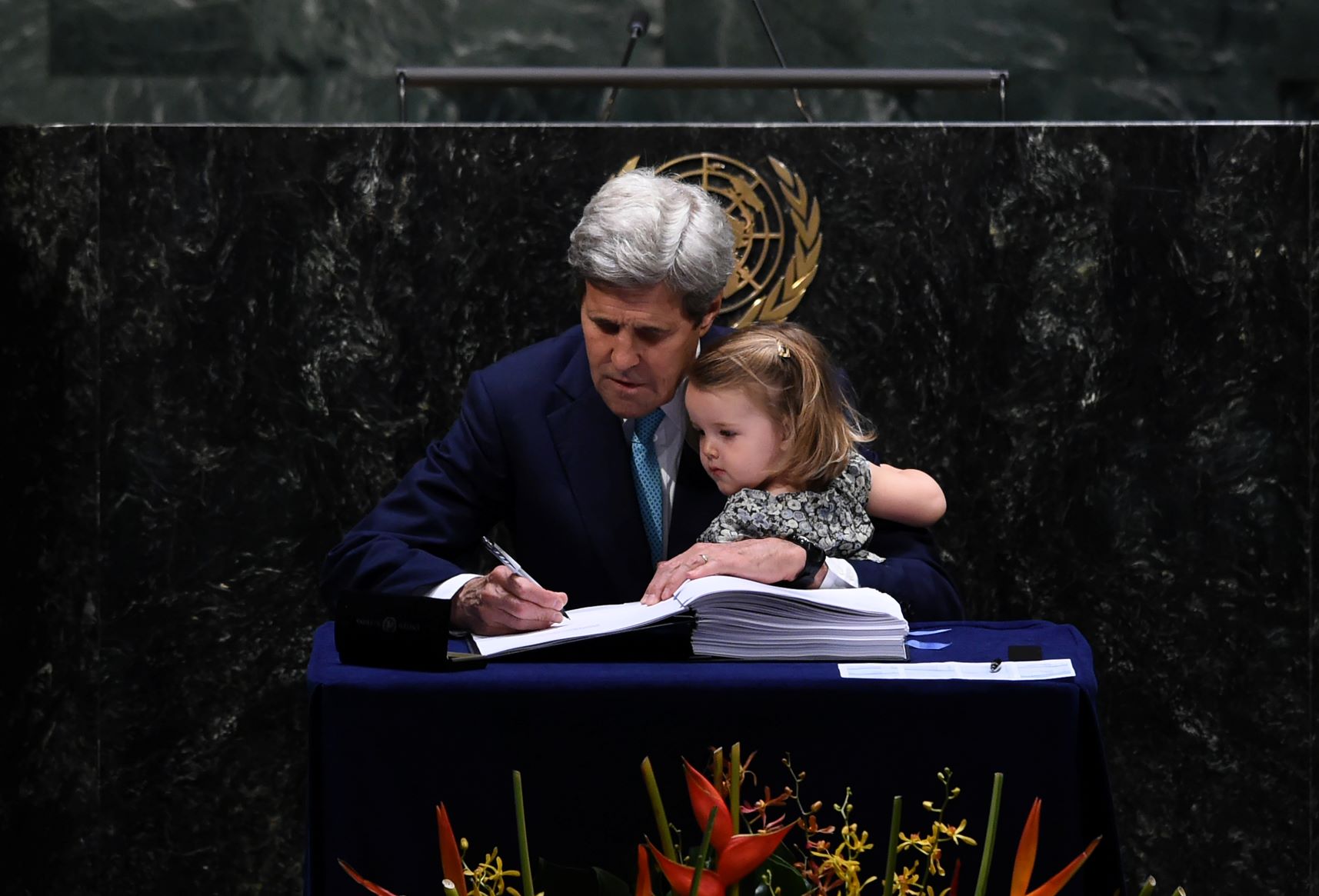 Então secretário de Estado dos EUA, John Kerry assina o Acordo de Paris, na sede da ONU em 2016, com a neta Isabelle no colo: experiência para lidar com questões climáticas globais e com parceiros internacionais em momento delicado (Foto: Jewel Samad/AFP)