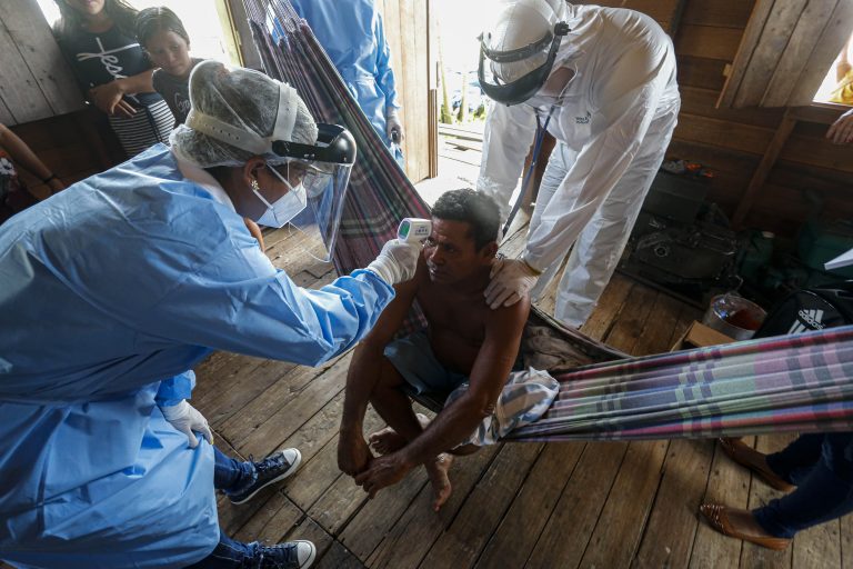 Agentes de saúde verificam a temperatura de um homem em uma comunidade ribeirinha do rio Murutipucu em Igarapé-Miri, Baixo Tocantins, no Pará. Foto Tarso Sarraf/AFP