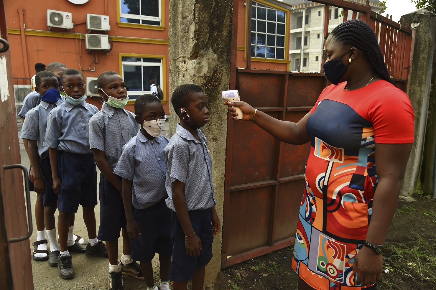 Foto Pius Utomi Ekpei/AFP. Janeiro/2021 Professora primária mede a temperatura dos alunos no portão do berçário Obele-Odan, em Surulere, Lagos, na Nigéria. Foto Pius Utomi Ekpei/AFP. Janeiro/2021