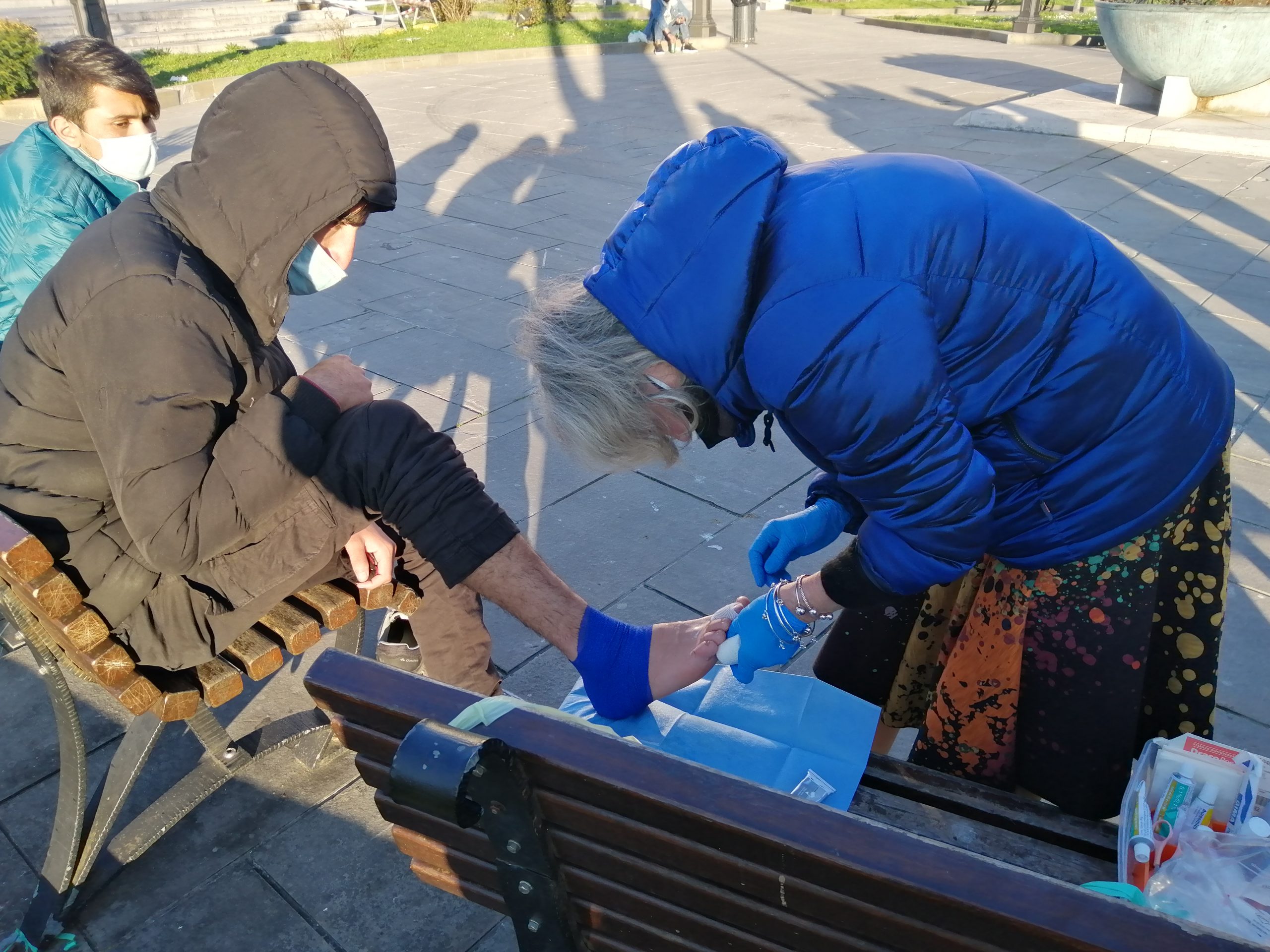 Na praça de Trieste, Lorena cuida da ferida no pé de um imigrante. Foto Janaina Cesar
