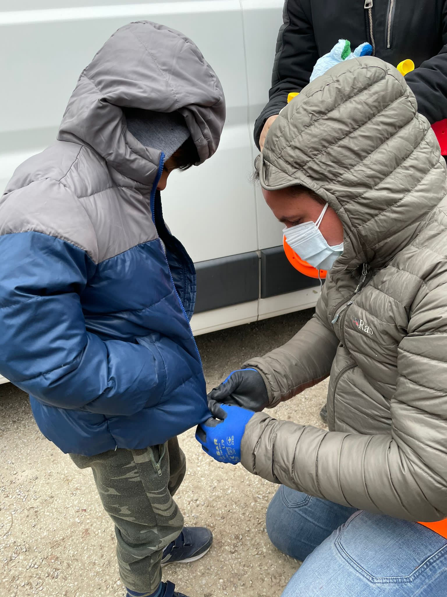 Jornada pela Bósnia: voluntário veste jaqueta em criança no campo de Hadžići. Foto Janaina Cesar