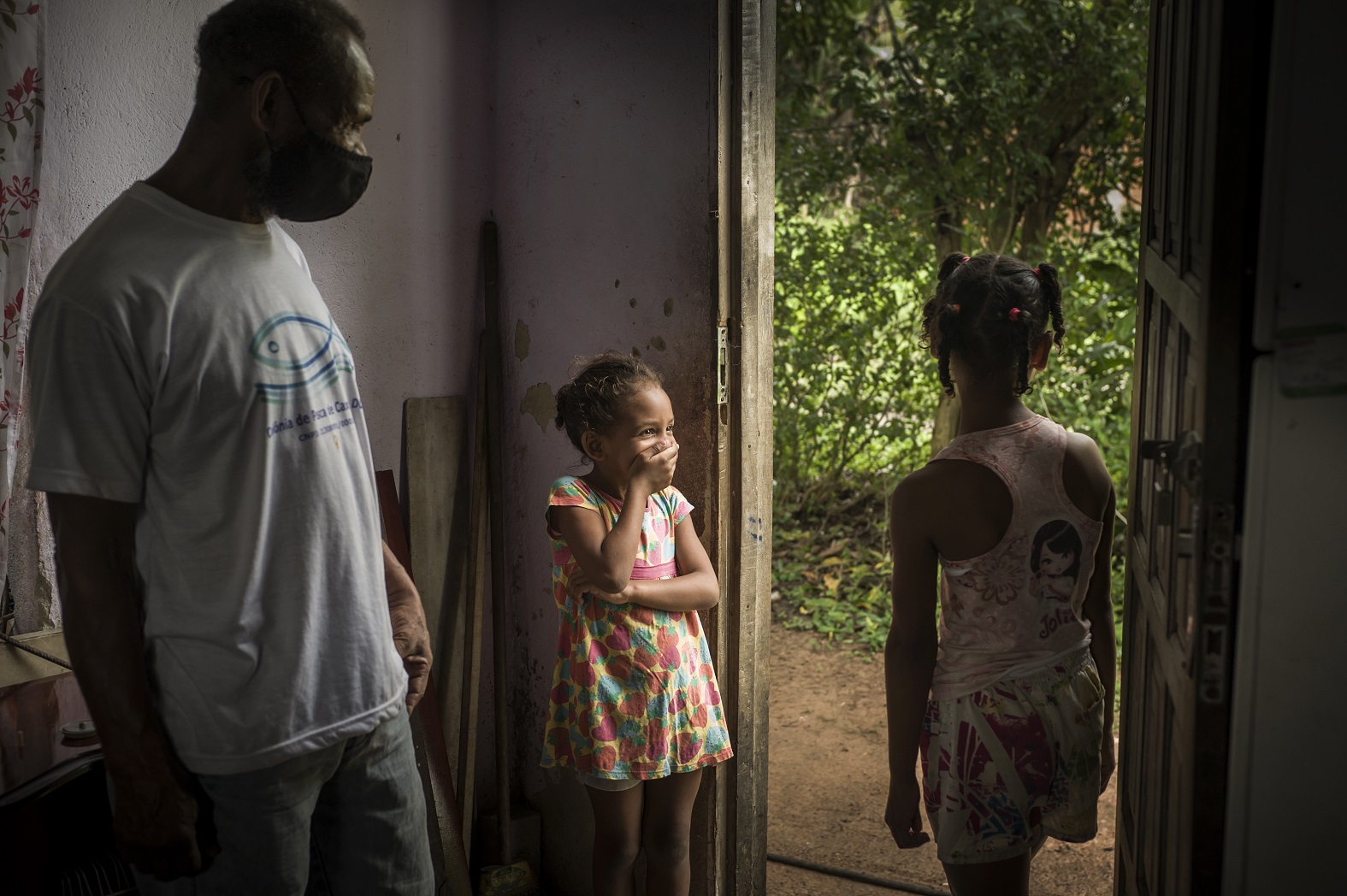 O pescador Gilciney Lopes Gomes, de camisa branca, morador de Caxias, Rio de janeiro, observa as filhas Camila Vitoria Dantas, 9 anos e Emanuela Dantas Gomes, 5 que estão com as vacinas atrasadas. Foto Marco Antonio Rezende/Colabora