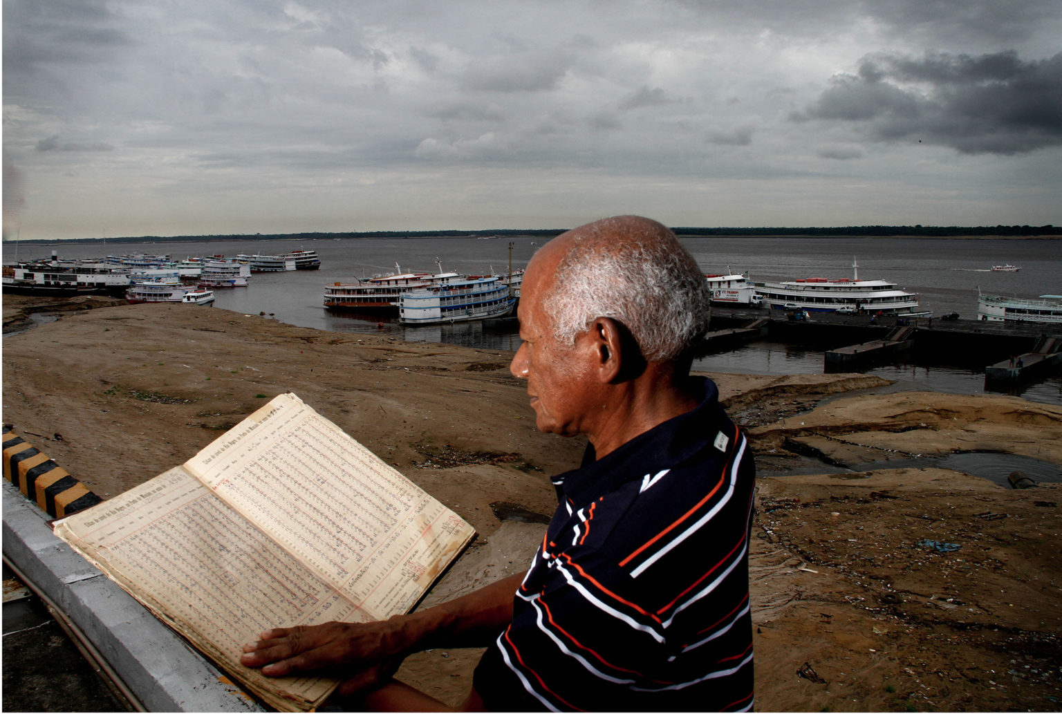 Valderino Pereira, em foto de antes da pandemia no período da seca, mostra o livro de registro diário da medição do rio Negro (Foto: Alberto César Araújo/Amazônia Real)