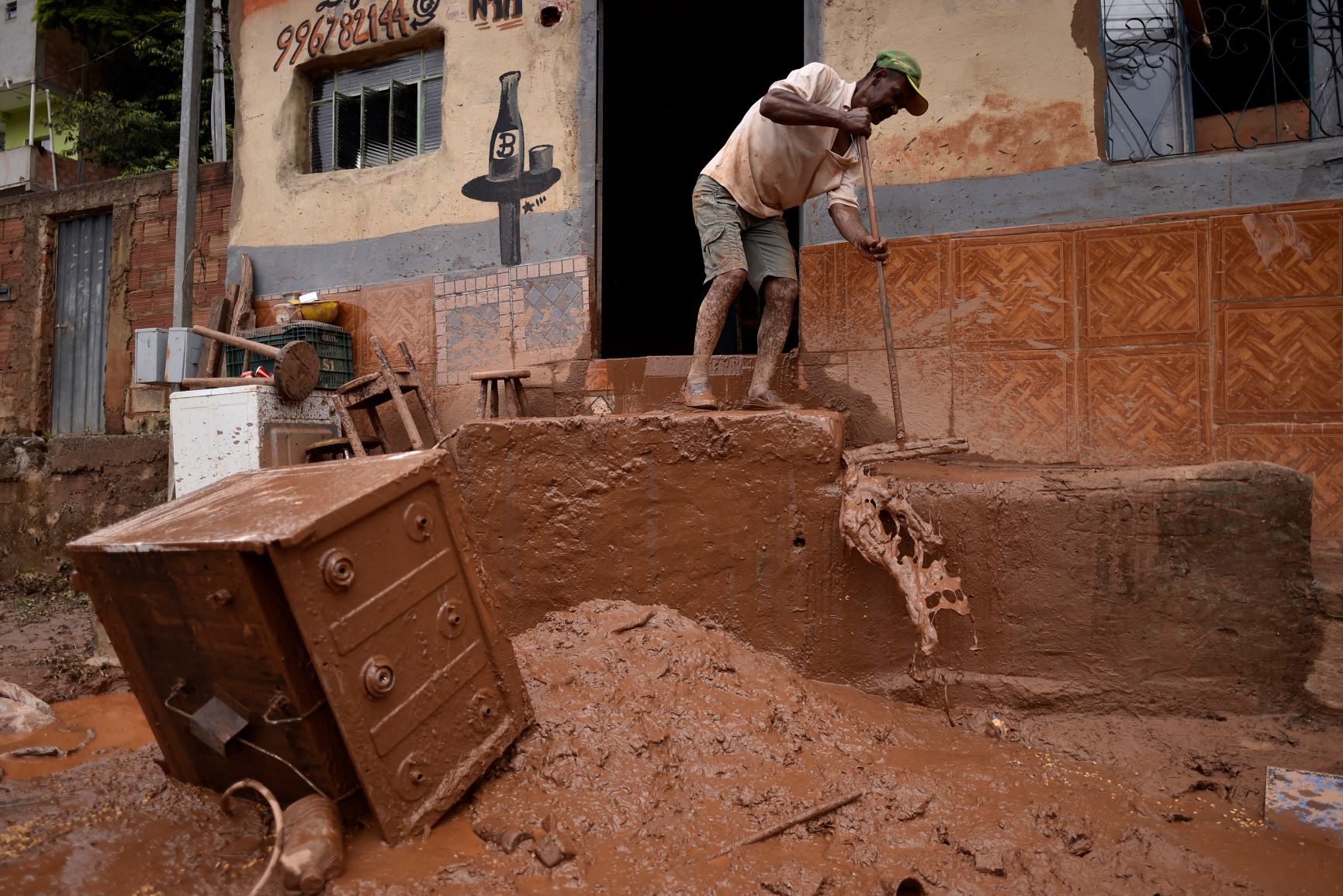 Morador tira lama de casa após temporal em Sabará, na Região Metropolitana de Beli Horizonte: estudo aponta que probabilidade de chuvas volumosas aumentaram 70% com industrialização e aquecimento global (Foto: Douglas Magno / AFP - 27/01/2020)