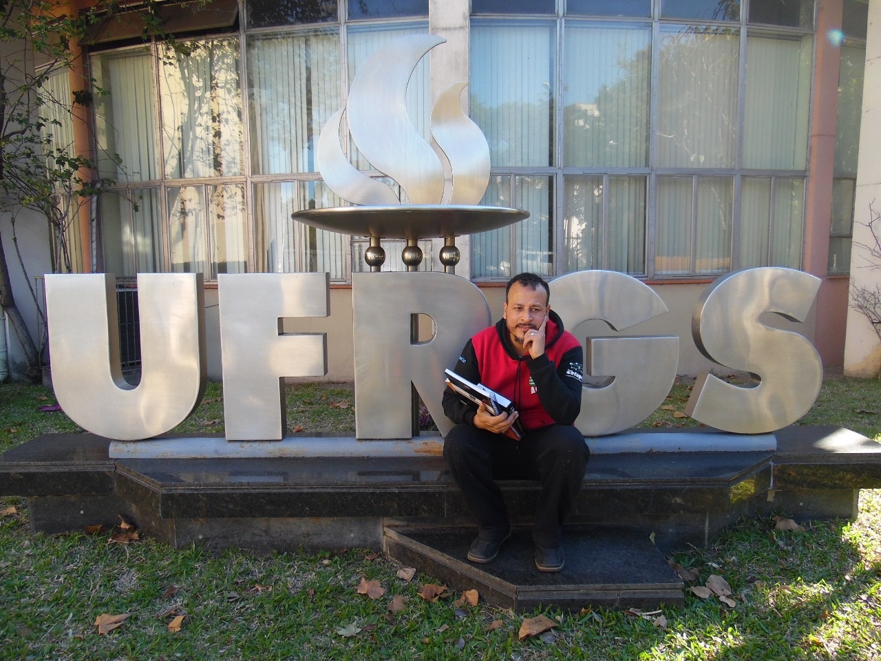 Foto Vinicius Cardoso Alexandro na porta universidade com o seu livro recém-lançado. Foto Vinicius Cardoso