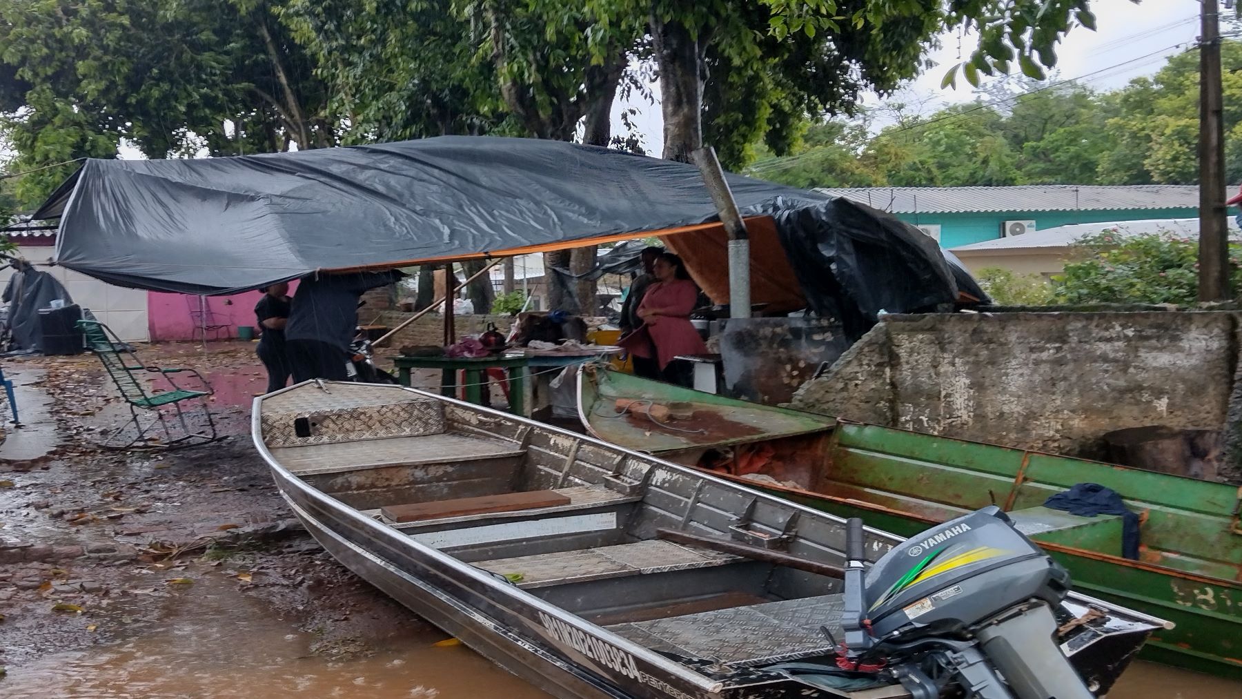 A pescadora Roseni (de casaco rosa) em barraca improvisada para vender peixes: balsa improvisada para salvar os móveis da casa e esperar a água baixar (Foto: Micael Olegário)