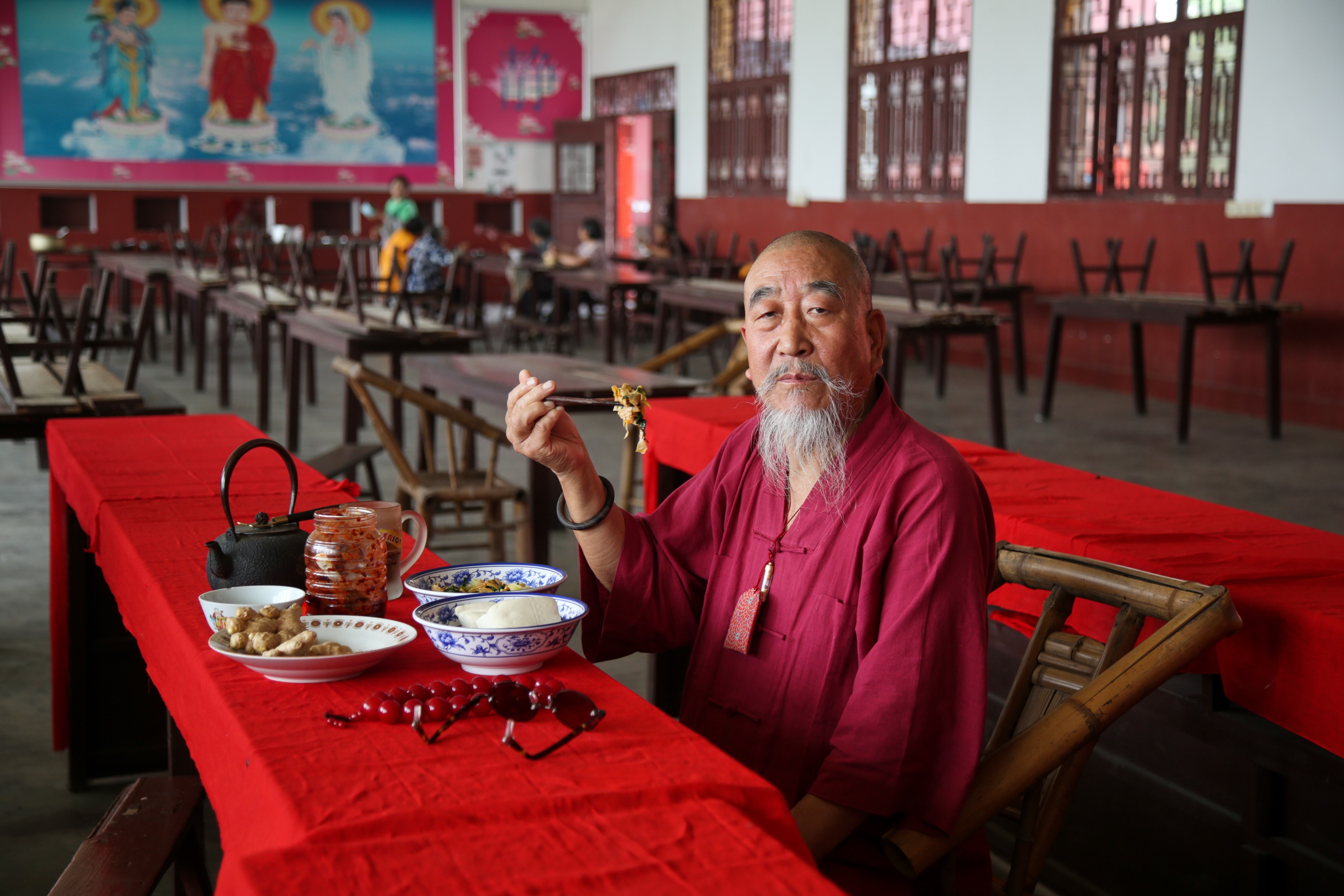 Pu Jing, monge budista, come prato de aipo frito com tofu no Templo Wanfu, na província de Sichuan, China. O tofu é um dos principais ingredientes da culinária vegetariana tradicional chinesa, muito ligada ao budismo. Foto Xiao Ye / Diálogo Chino