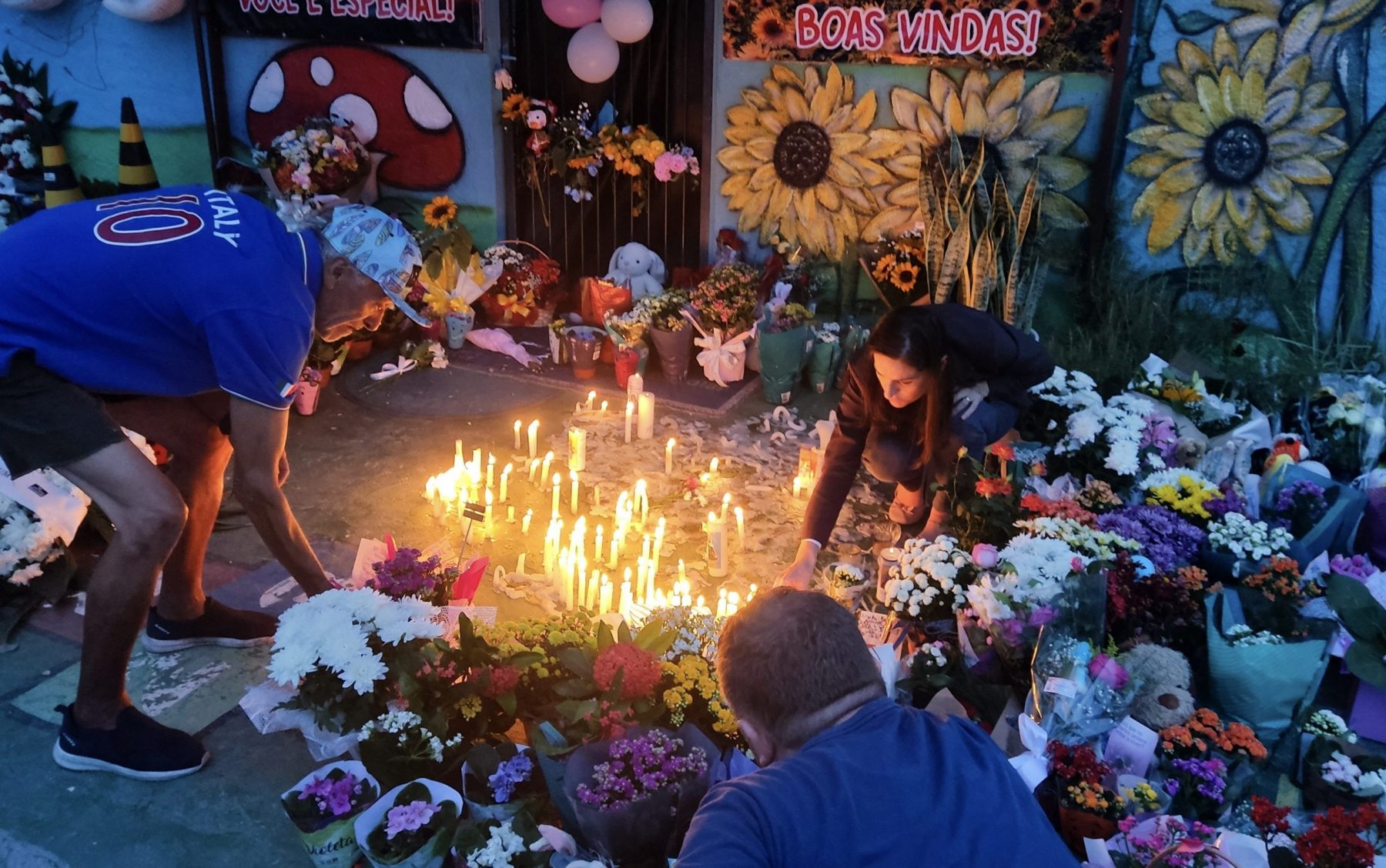 Pessoas acendem velas durante vigília em frente à pré-escola particular do Centro Bom Pastor, em Blumenau, Santa Catarina. Um agressor de 25 anos invadiu a creche particular e matou quatro crianças com arma branca antes de se entregar à polícia. Foto Anderson Coelho/AFP
