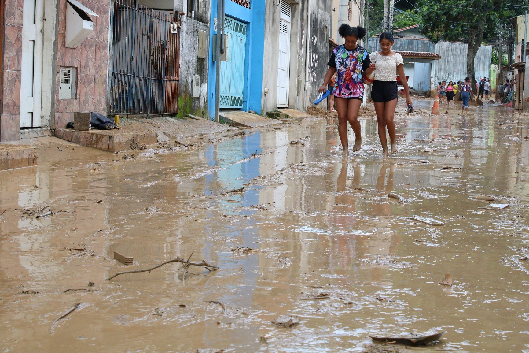 Moradoras caminham entre poças d'água após temporal em São Sebastião, no litoral paulista: clima extremo facilita proliferação do mosquito da dengue (Foto: Rovena Rosa / Agência Brasil - 20/02/2023)