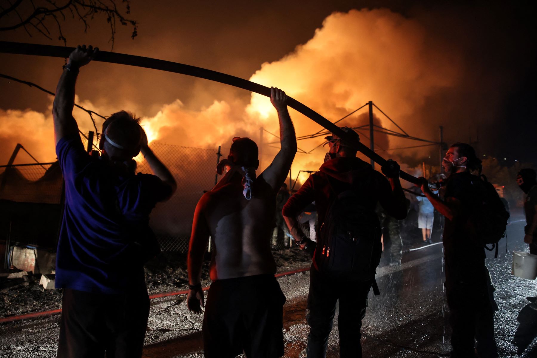 Voluntários ajudam a combater incêndios na periferia de Atenas: milhares de pessoas evacuadas pela ameaça do fogo (Foto: Aris Oikonomou / AFP)